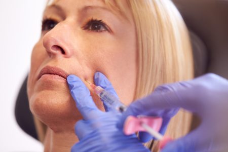Close Up Of Mature Woman Sitting In Chair Being Give Botox Injection By Female Doctor