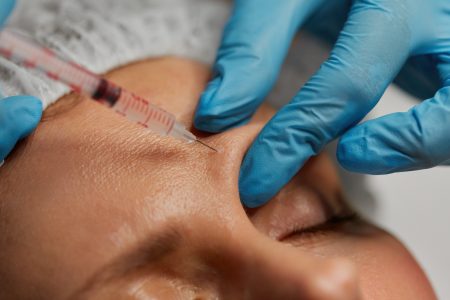Closeup cosmetologist hand with syringe injecting liquid into human skin