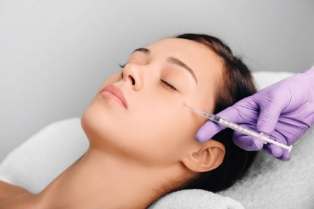 Woman receiving Botulinum Toxin Injection injection into eyes area .